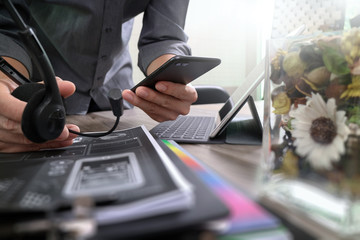 Man using VOIP headset with digital tablet computer docking keyboard,smart phone,concept communication, it support, call center and customer service help desk,vase flowers on wooden table