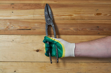 Sharp metal tin snips on vintage wooden board top view construction concept.