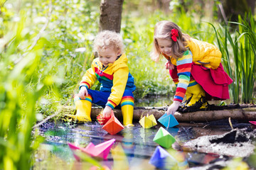 Kids playing with colorful paper boats in a park
