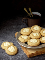 Delicious homemade cookies. Shortbread with cream cheese and cup of tea on dark background. Copy space.