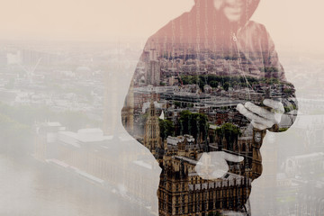 Double exposure of hipster male in a hood hand using mobile phone,front view,London architecture buildings