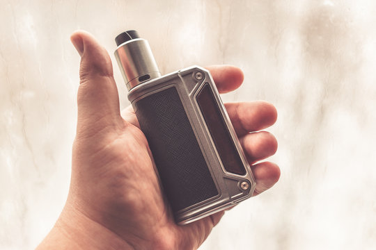 Vaping device in the man's hand. Electronic cigarette or e-cig mod , vape