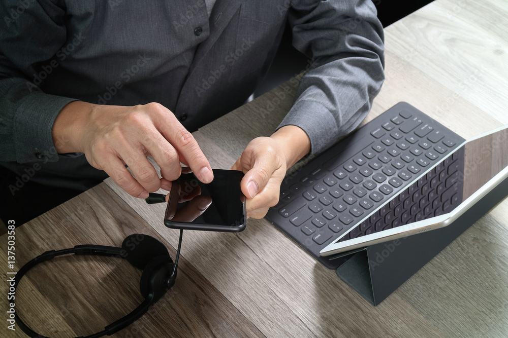 Aufkleber top view of man hand using VOIP headset with digital tablet computer docking keyboard,smart phone,concept communication, it support, call center and customer service help desk on wooden table