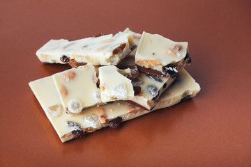 white chocolate with nuts, raisins on a brown background