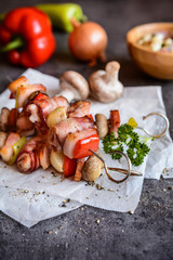 Grilled skewers with rabbit meat wrapped in a bacon with onion, mushrooms and pepper