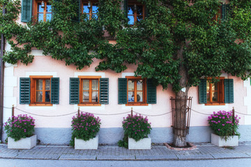 Fototapeta na wymiar Typical Austrian Alpine house with bright flowers on the balcony