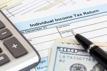 Tax form with calculator, pen, and dollar banknote; document are mock-up