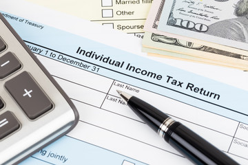 Tax form with calculator, pen, and dollar banknote; document are mock-up