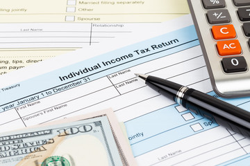 Tax form with calculator, pen, and dollar banknote; document are mock-up