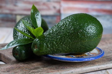 Green ripe avocado with leaves on granite plank