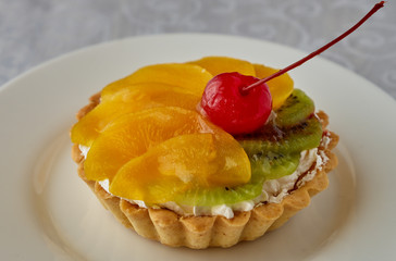 Tartlets with cream and fruit. Cherry, peach and kiwi.