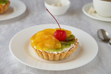 Tartlets with cream and fruit. Cherry, peach and kiwi.