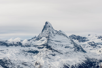 Scenic moody view on snowy Matterhorn peak with sky and clouds in background, Switzerland.