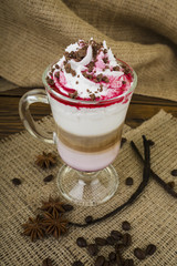Coffee Latte. Coffee with whipped cream topping in a tall glass on a wooden background with burlap