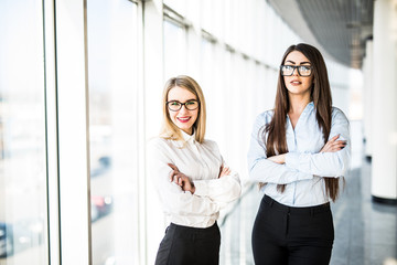Obraz premium Young business ladies in office hall over panoramic windows.
