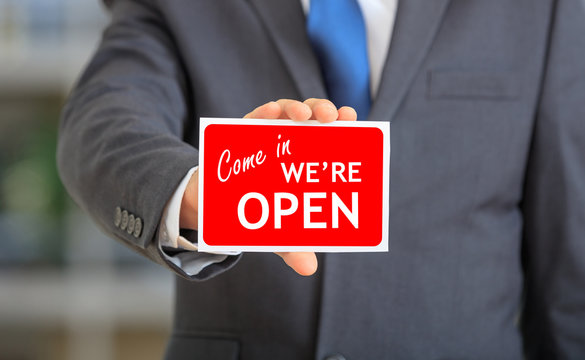 Man holding a we are open sign