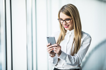 Business woman text sms on phone in modern office