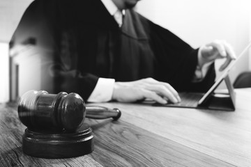 justice and law concept.Male judge in a courtroom with the gavel,working with digital tablet...