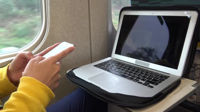 4K Asian young woman sit down near to the window in higth speed rail checks her phone and computer, writting SMS text with friend using Line, social network, she waits for arrive her stop station-Dan