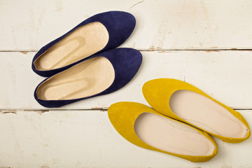 Blue and yellow women's shoes (ballerinas) on wooden background.
