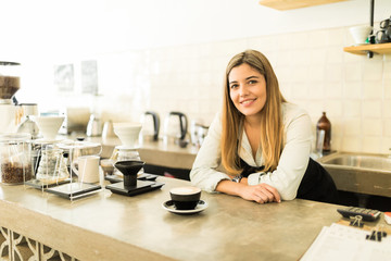 Pretty female barista with a cup of coffee