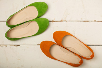 Green and orange women's shoes (ballerinas) on wooden background.