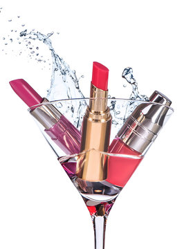 Fototapeta Three types of  moisturizing lipstick stand in the martini glass with big water splash above the glass