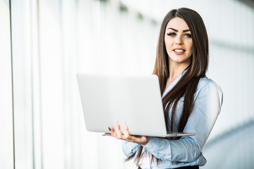 Obraz premium business woman with laptop in office with panoramic windows.