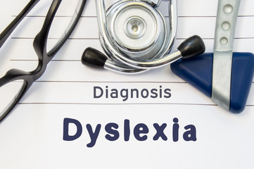 Neurological diagnosis of Dyslexia. Neurological hammer, stethoscope and doctor's glasses lie on doctor workplace on sheet of notebook, labeled with the title of medical diagnosis of Dyslexia - obrazy, fototapety, plakaty