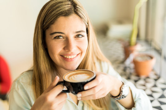 Happy Girl Drinking A Cup Of Cappuccino