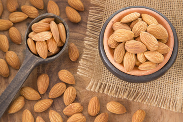 Almonds in bowl on wooden background