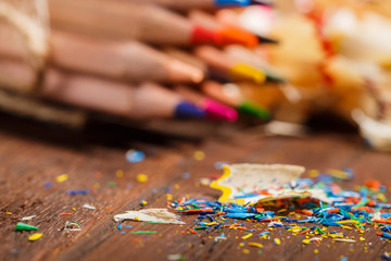 Wooden colorful pencils with sharpening shavings, on wooden table