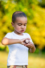 Adorable little black boy eating ice cream cone on the street