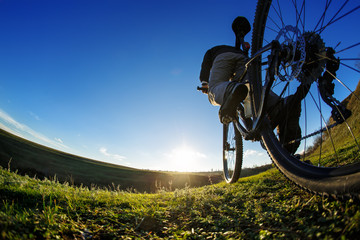 Fototapeta na wymiar Detail of cyclist man feet riding mountain bike on outdoor trail in sunny meadow