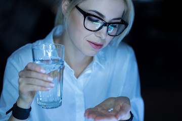 Young woman taking tablets at work