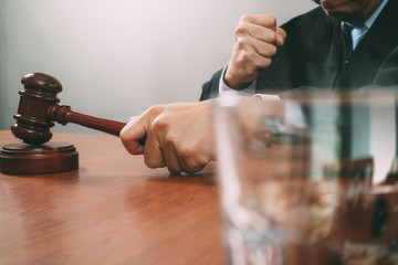 justice and law concept.Male judge in a courtroom with the gavel,working with smart phone,digital tablet computer docking keyboard on wood table,filter effect