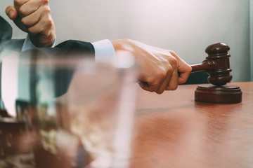 justice and law concept.Male judge in a courtroom with the gavel,working with smart phone,digital tablet computer docking keyboard on wood table,filter effect