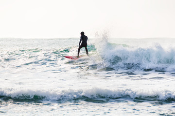 Surfing and blue wave in ocean. Surfing in wetsuit