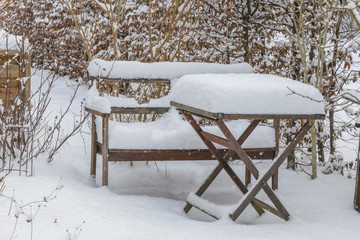 Schneebedeckter Gartentisch mit Bank im Winter