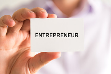 Businessman holding a card with text ENTREPRENEUR