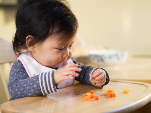 baby girl eating  vegetable first time at home
