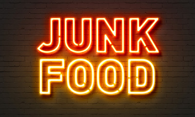Junk food neon sign on brick wall background.