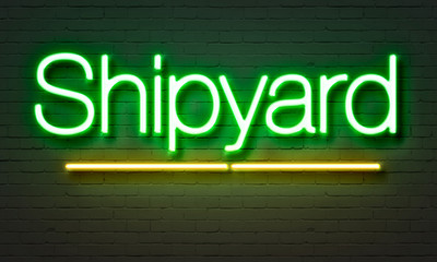 Shipyard neon sign on brick wall background.