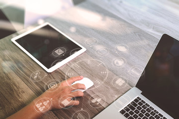 hand using mouse and laptop computer with digital tablet in modern office with virtual screen interface icons diagram as concept