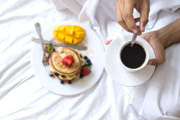 Hotcakes with fruit and coffee in bed