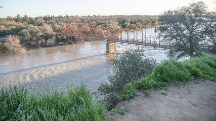View of the red bridge, Fair Oaks, from the bluffs, with American River in flood