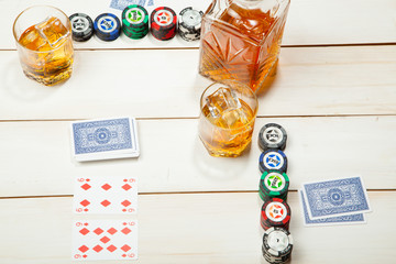 game of poker and a glass  whiskey with ice on  white wooden background