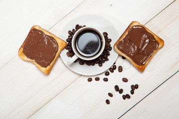 cup of coffee and toast with chocolate on a white wooden table