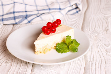 Vanilla cheesecake on a white plate, decorated red currant, close up