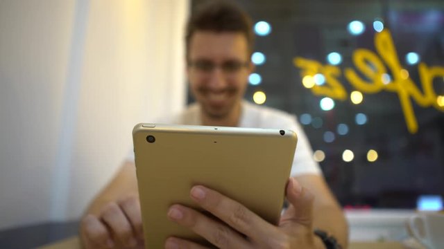 4K Caucasian Man is smiling happiness when using tablet touch screen to chat and contact people on the distance in a coffeeshop. European Man checks social network with modern wireless technology-Dan